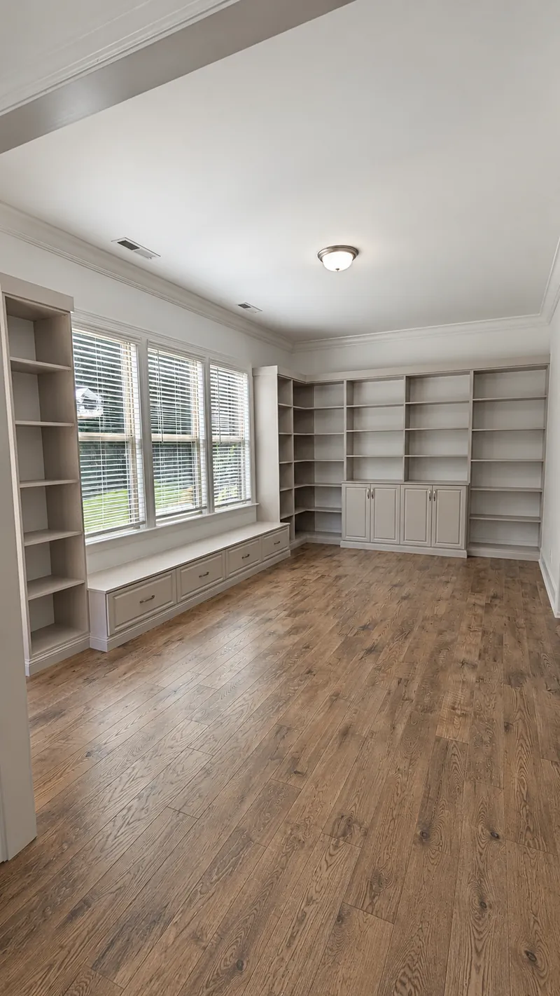 Room with built-in bookcases, base cabinets and a window seat with drawers