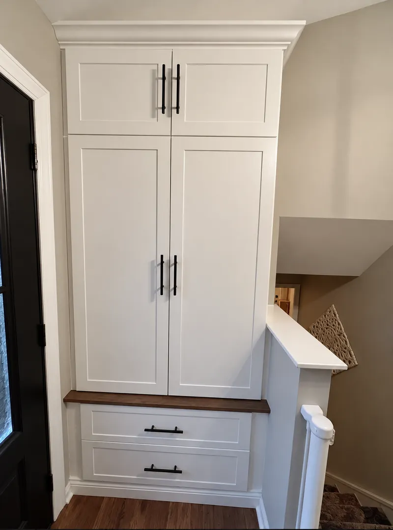 White entry cabinet with a wood bench seat and drawers beside the front door