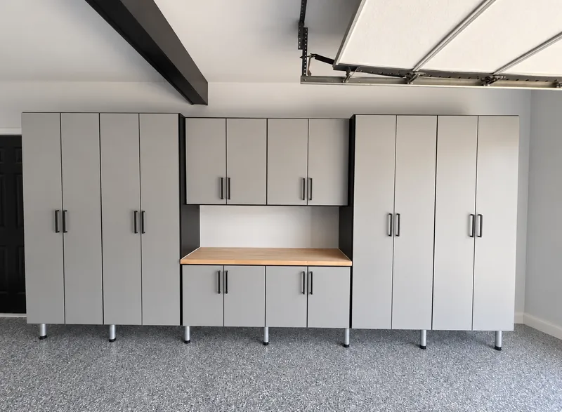 Gray garage cabinet wall with tall cabinets, upper cabinets and a butcher-block workbench