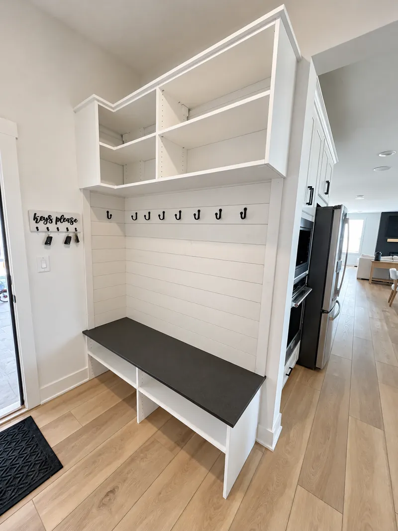 White mudroom bench with shiplap backing, coat hooks and open upper shelving
