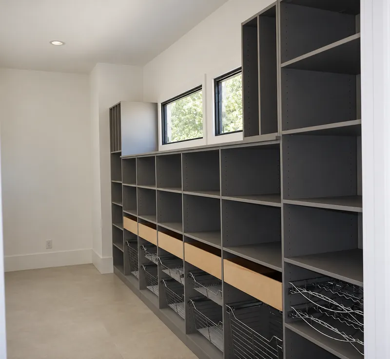 Walk-in pantry with gray open shelving, wood-front drawers, wire pull-out baskets and wine racks