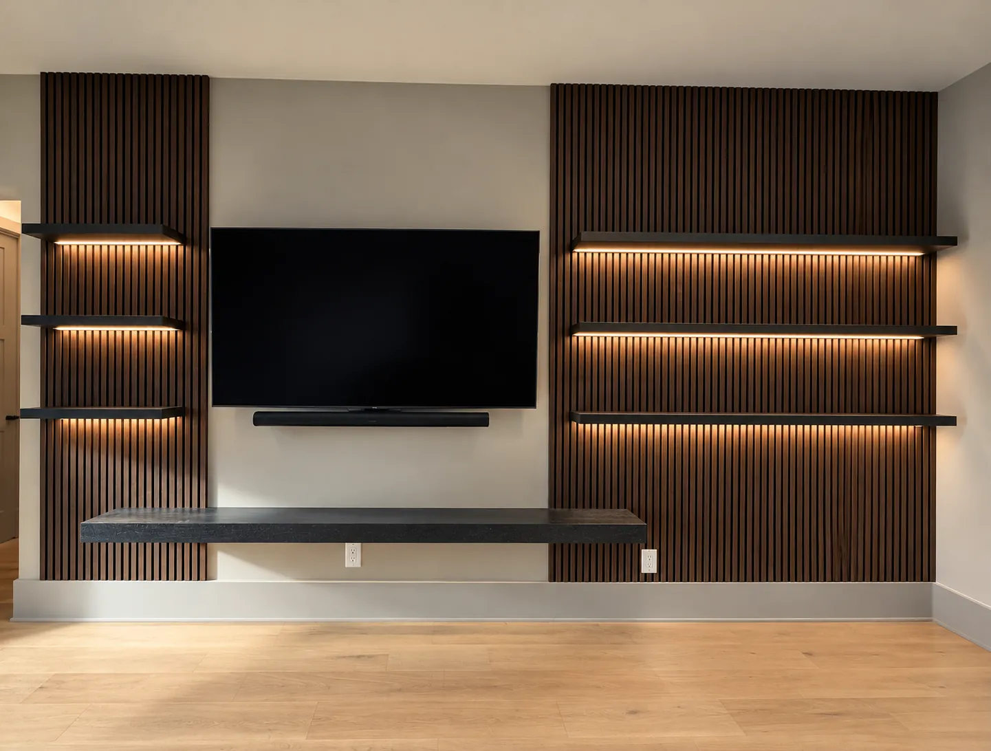 Media wall with walnut slat wall panels, LED-lit floating shelves and a long floating shelf beneath a wall-mounted TV
