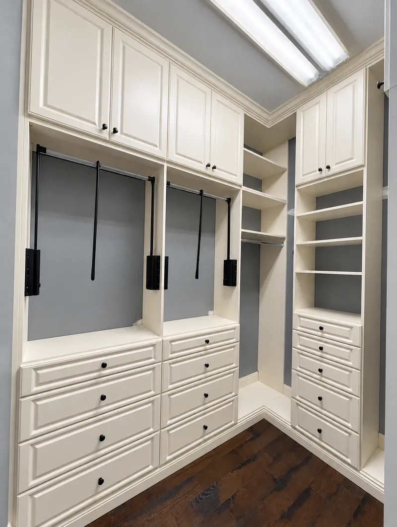 Closet with cream raised-panel cabinets, pull-down wardrobe rods and drawer stacks