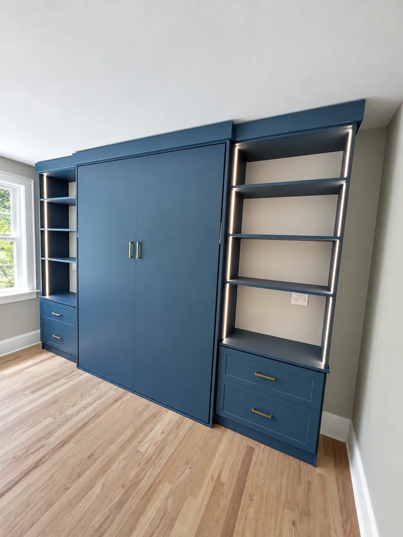 Blue wall bed cabinet flanked by shelving with LED lighting and drawers